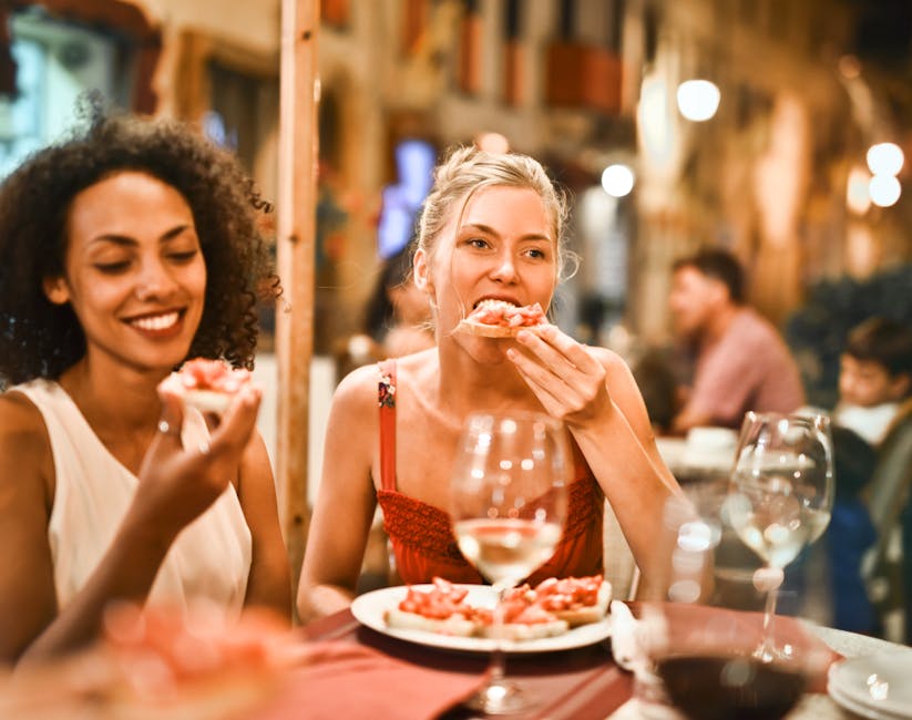 Two women enjoying bruschetta and wine at a vibrant outdoor restaurant