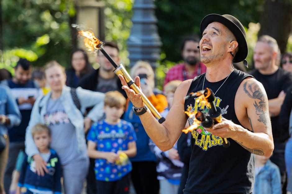 A skilled street performer juggles fire, entertaining a diverse audience in an urban setting.
