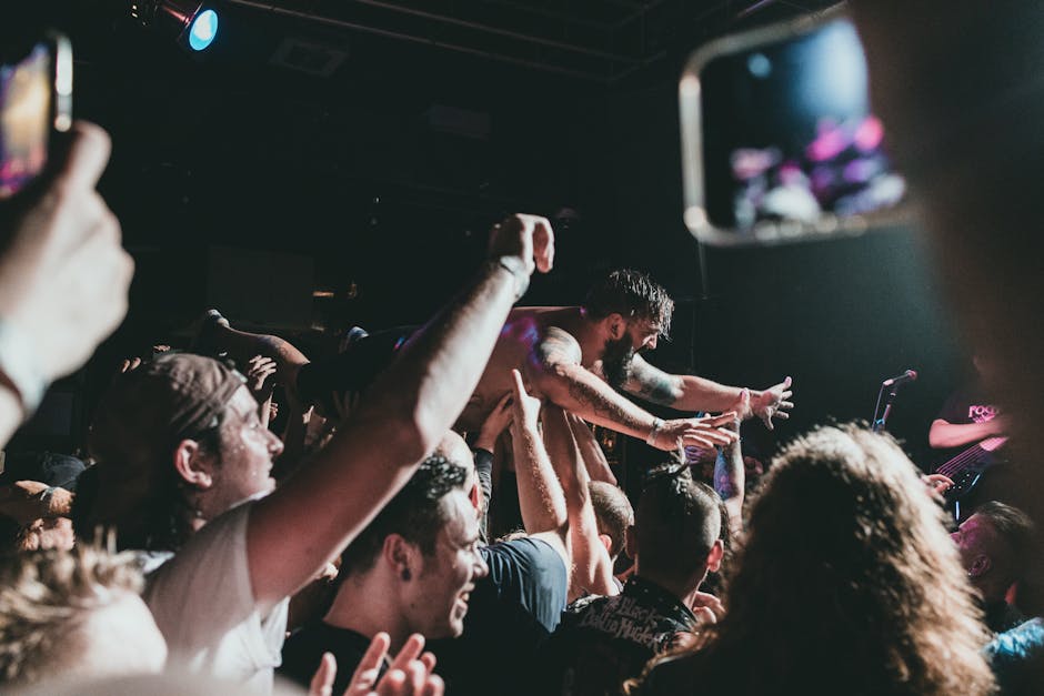 Vibrant concert scene with a musician crowd surfing under stage lights.