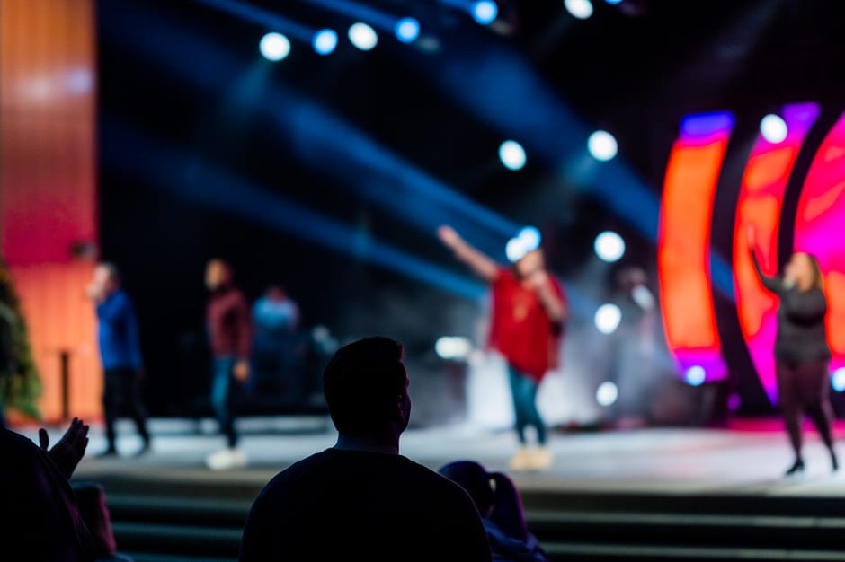 An energetic live concert with colorful stage lights and a captivated audience in an indoor setting.